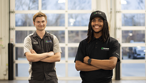 Two mcgrath service techs stand on the service bay floor